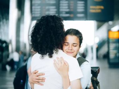 Emotional moment of saying goodbye at an airport, representing transitions and personal growth in therapy with Susanna Wright